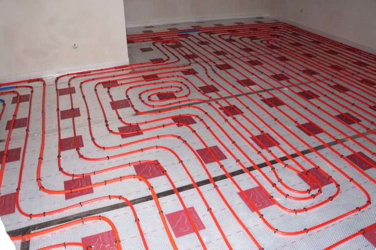 Red PEX radiant floor heating loops installed on a subfloor